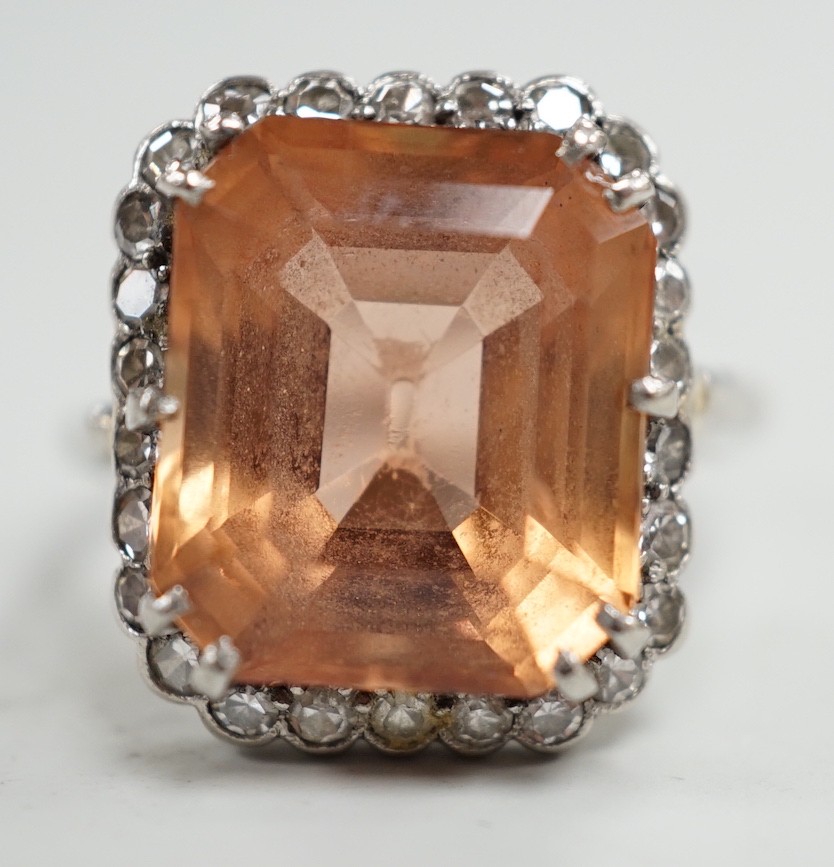 A white metal and emerald cut orange/peach topaz set dress ring, with diamond set border, size I/J, gross weight 6.1 grams.